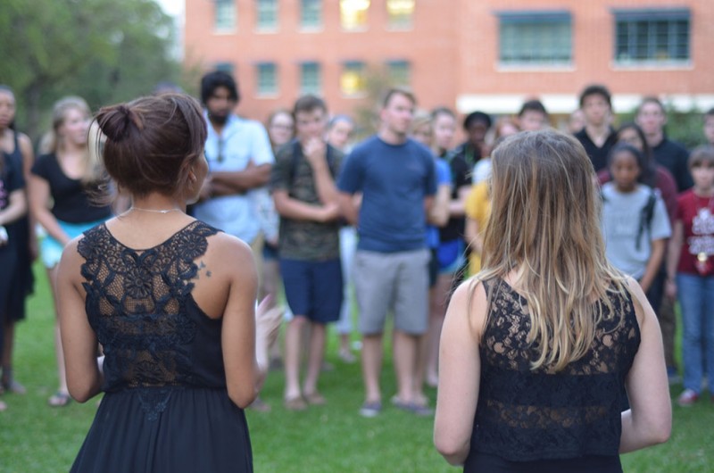 First years Sydney Wright and Hayley Says, friends of Sheena, talk about her love of music, horseback riding and travel, as members of the community look on during the memorial held at 8 p.m. on Tuesday. Photo by Matthew Brink.