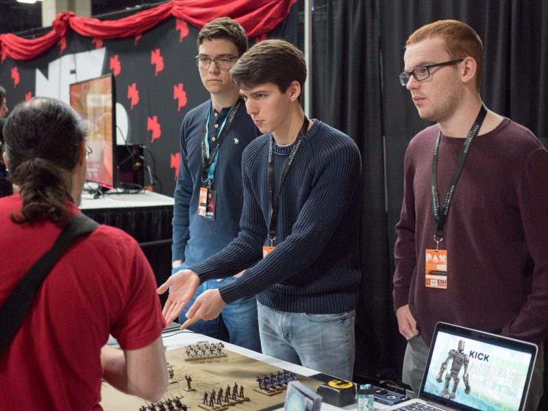 James Lovett, center, explains his game Crusade of Two Suns to an interested PAX attendee. His brother Brock Lovett, left, and coworker Marshall Tickner, right, accompanied James at the companys booth for all three days of the convention. photo by Amani Canada, photo editor