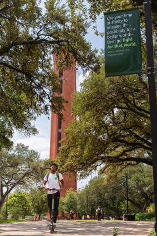 A Trinity student rides a scooter in front of Murchison Tower.