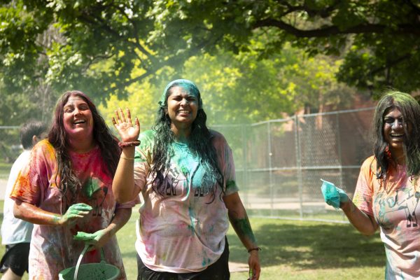 Sophomores Khushi Kakadia, Diya Contractor, and Riya Vankamamidi smiling after throwing gulal on each other. 