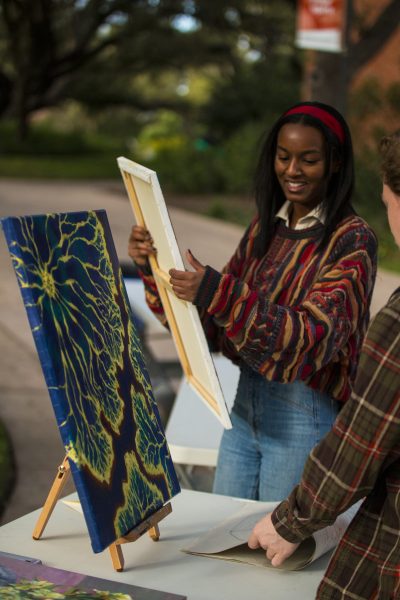 Senior Lauren Dotson places her artwork for sale on stands for Art Market