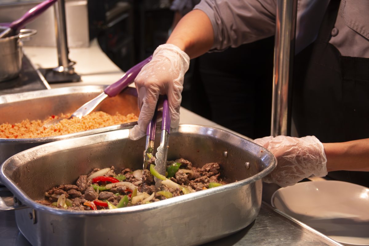 Gloved Mabee worker stirs food for students