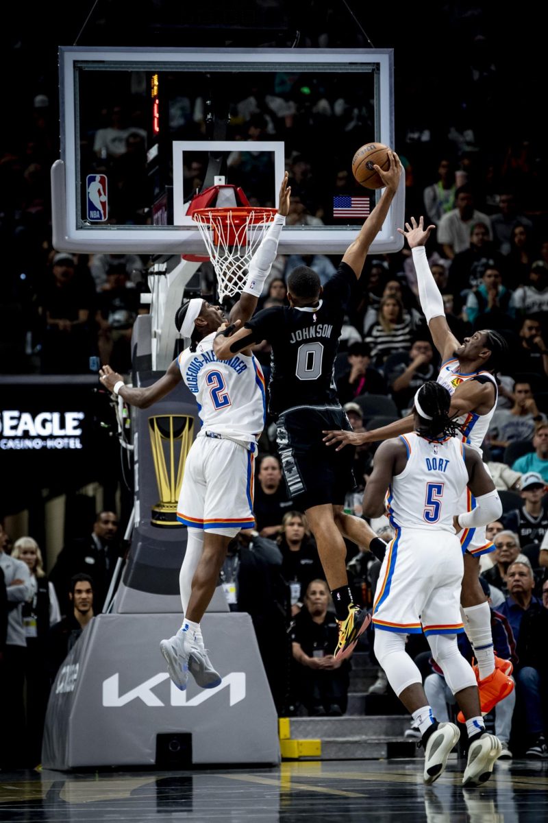 Spurs forward Keldon Johnson soars for a dunk over OKC Thunder guard Shai Gilgeous-Alexander.