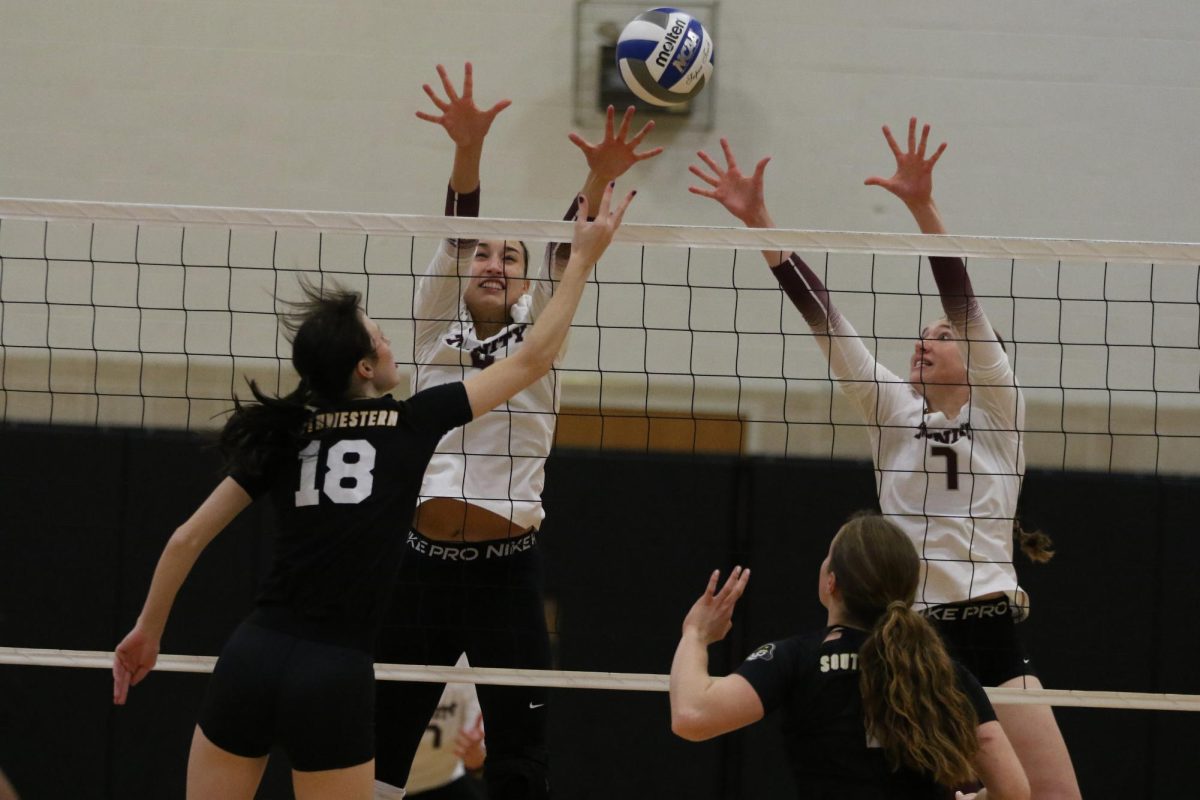 Fifth-year middle blocker Maddie Fate and junior outside hitter Reagan Whatley reach to block an attack by Southwestern middle blocker Brooklyn Spikes.