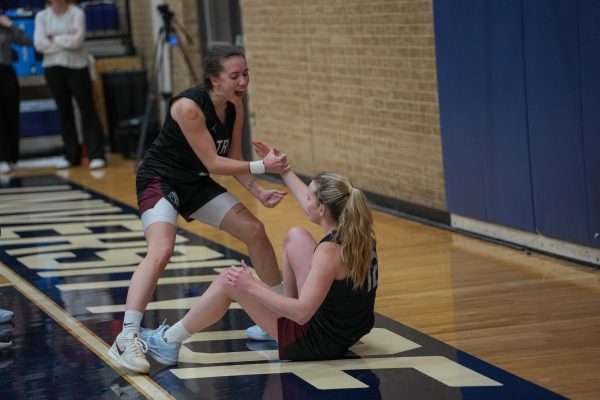 Junior guard Kylie Minter celebrates a TLU foul as she helps up first-year guard Livy Sauvageau.