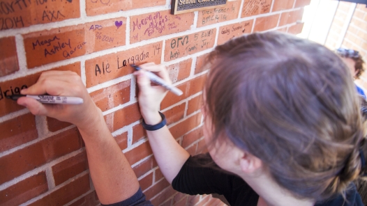 Students leave their marks by signing bricks after donating to the senior class gift.