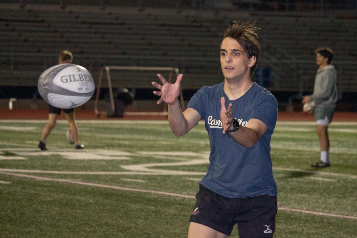 First year Dawson Sotiriades catches a pass from a teamate during warmups on the football field.